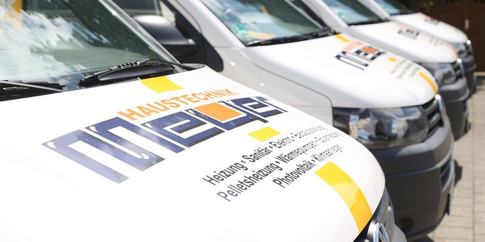 Nahaufnahme der Motorhaube eines Lieferwagens, auf dem die Dienstleistungen wie Heizung und Sanitär deutlich sichtbar sind.