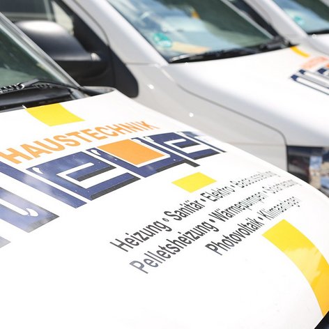 Nahaufnahme der Motorhaube eines Lieferwagens, auf dem die Dienstleistungen wie Heizung und Sanitär deutlich sichtbar sind.