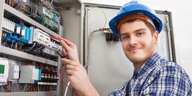 Ein junger Elektroniker überprüft einen Verteilerkasten